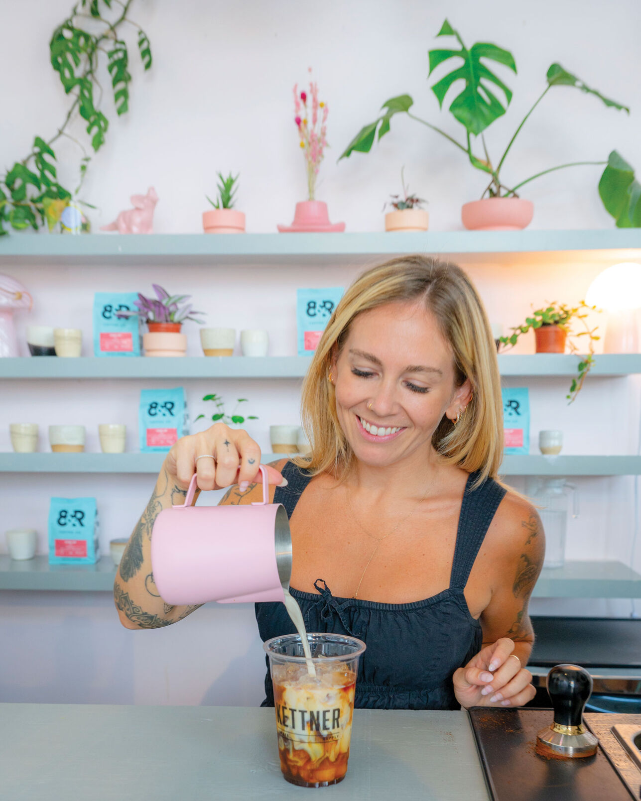 A woman pours milk into a plastic cup labeled Kettner